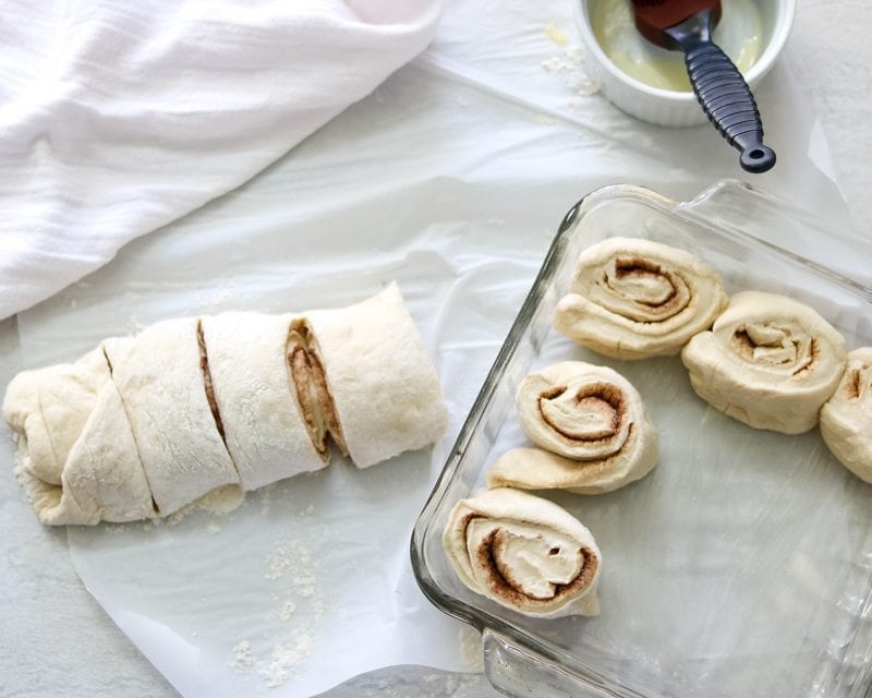 Cinnamon roll dough being arranged in baking pan.