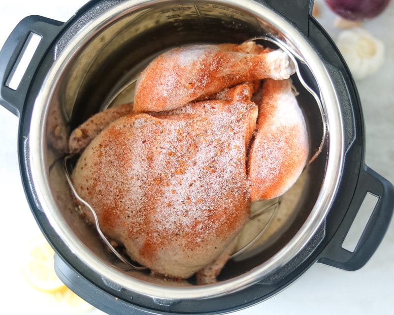 Pressure Cooker with whole chicken in it seasoned with rotisserie flavoring