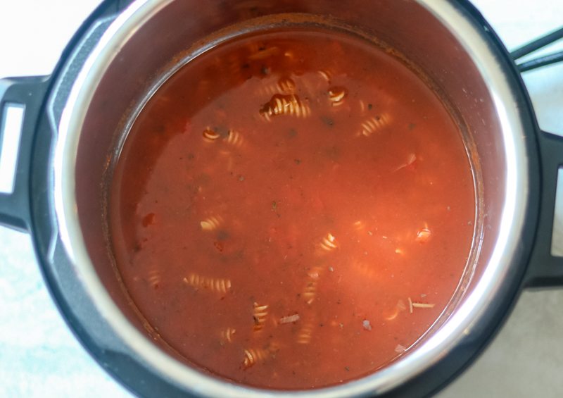 Instant Pot filled with tomato sauce and rotini noodles just sumberged in the sauce