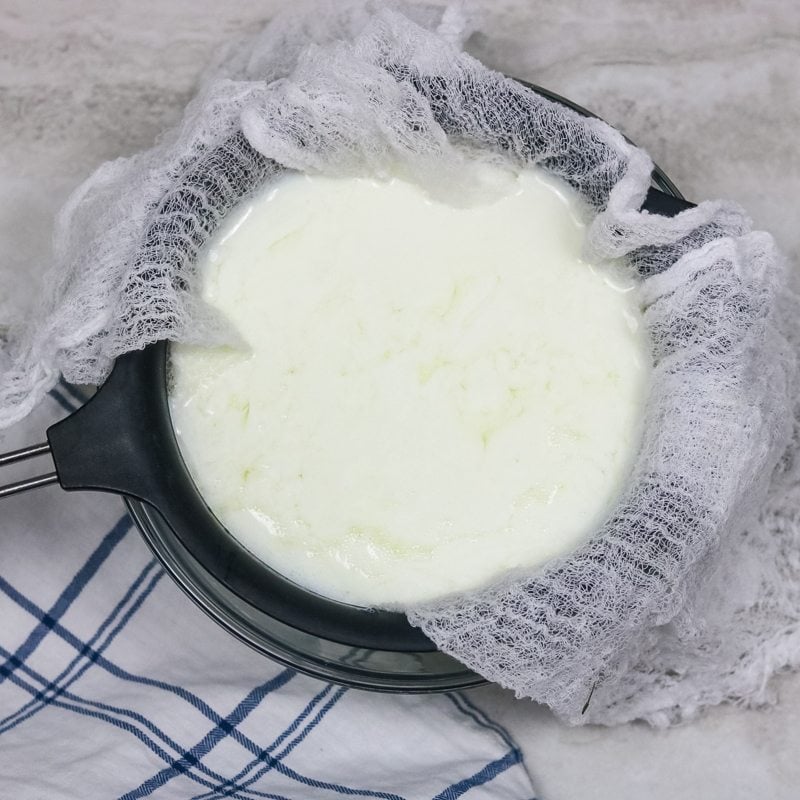 Plain yogurt straining over cheesecloth
