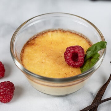 Ramekin with creme brulee topped with fresh raspberries and mint.