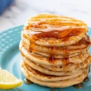 Stack of whole wheat pancakes on plute plate topped with syrup