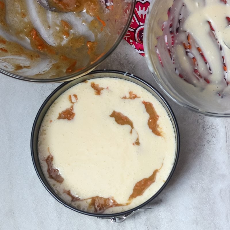 Cheesecake and carrot cake batter marbled together in springform pan for pressure cooker