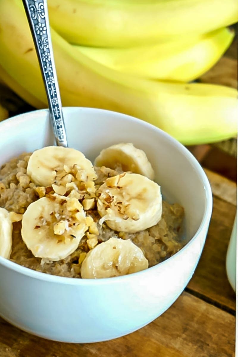 Breakfast Quinoa in white bowl topped with bananas and chopped nuts