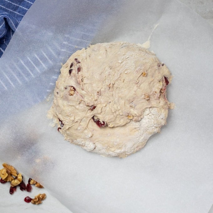 Bread dough shaped in circle on parchment paper.
