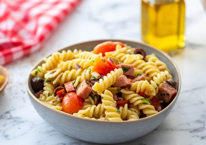 Italian Pasta Salad in bowl with olive oil off to side.