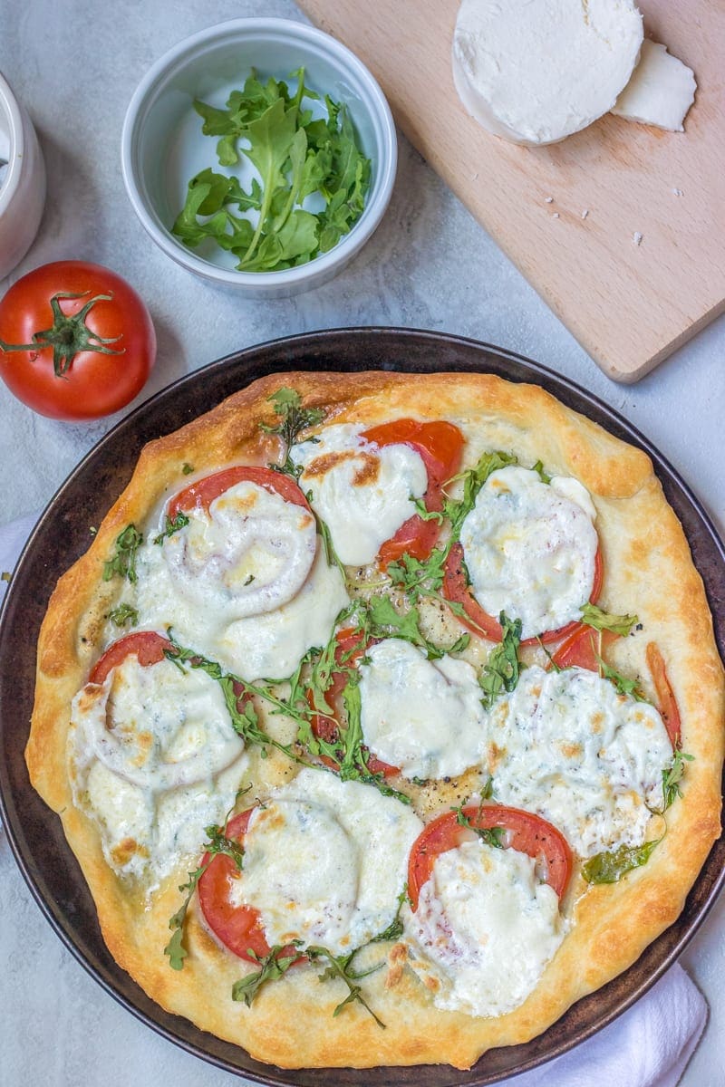 Tomato Pizza on pizza pan with fresh tomatoes in background. 