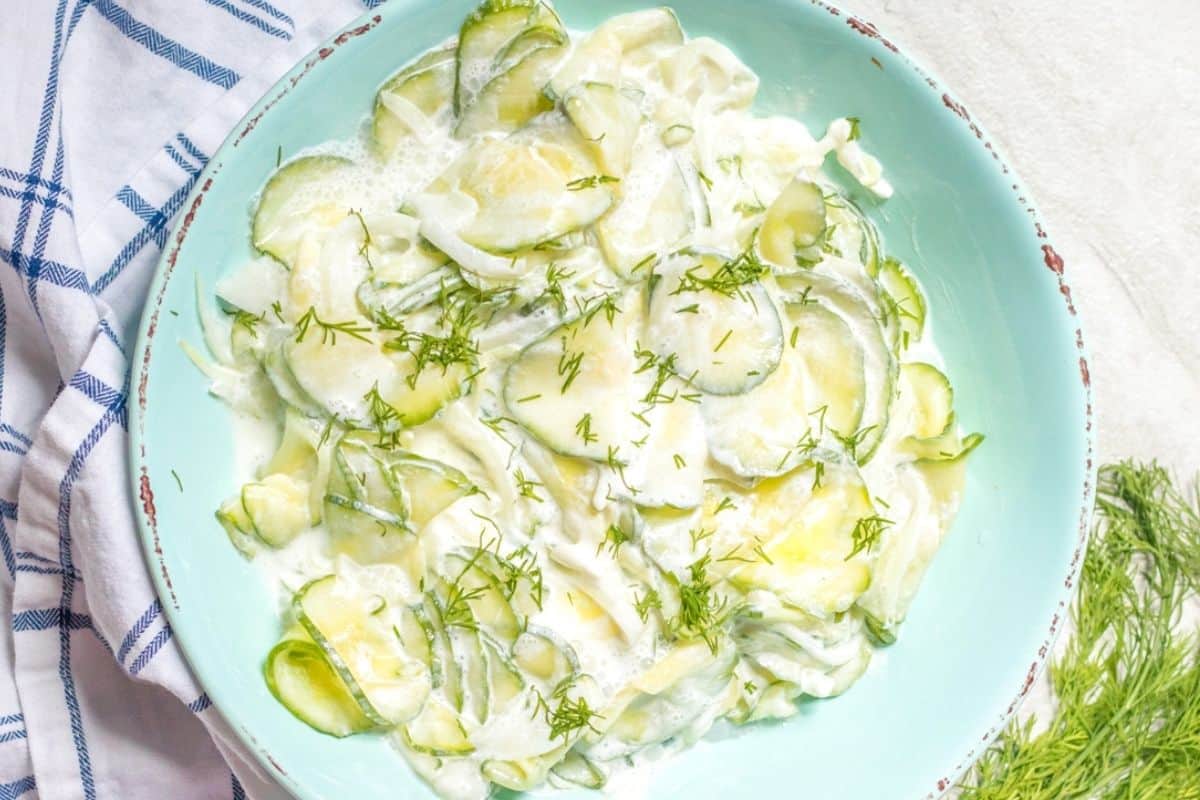 Creamy cucumber salad with dill in blue mixing bowl. 