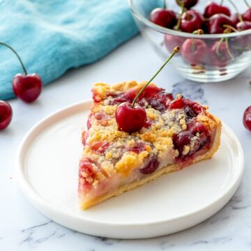 Slice of Cherry Pie on White Plate with fresh cherry on top