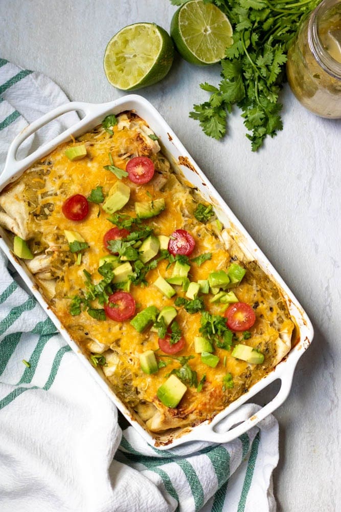 Cheesy Chicken Enchiladas topped with cilantro, tomatoes, and avocados