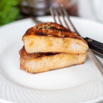 Chuletas de cerdo a la parrilla con salsa de miel y ajo en plato blanco