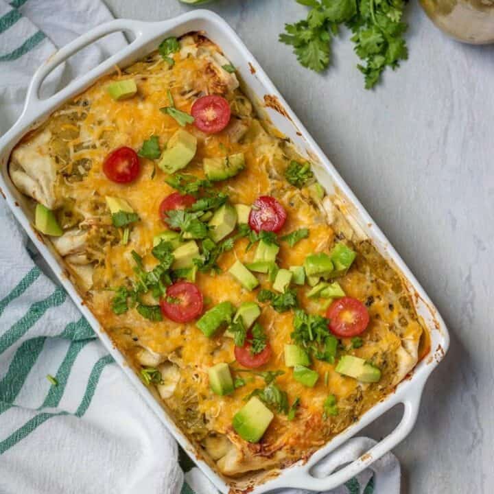 Baked Chicken Enchiladas topped with avocado, tomatoes, and cilantro