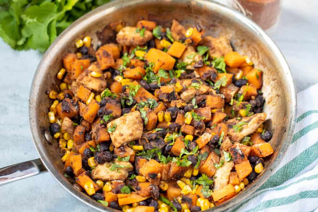 Sweet potatoes and chicken in skillet with beans and corn.
