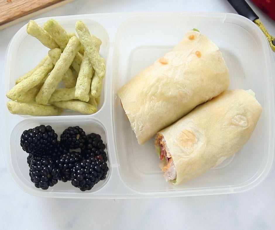 Turkey Club Wrap in lunch Container with snap pea crisps and blackberries