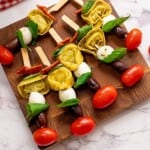 Antipasto Skewers with tomatoes and mozzarella on wooden cutting board ready to be served.