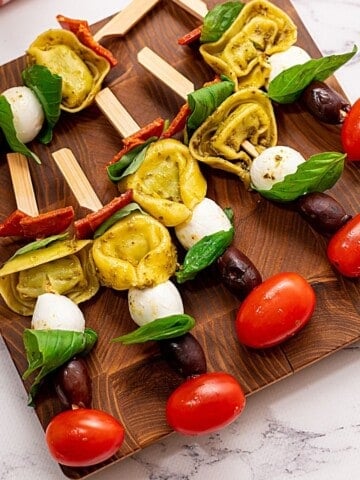 Antipasto Skewers with tomatoes and mozzarella on wooden cutting board ready to be served.