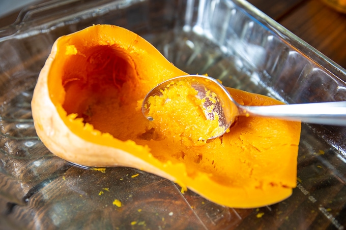 Spoon Scooping out flesh of butternut squash.