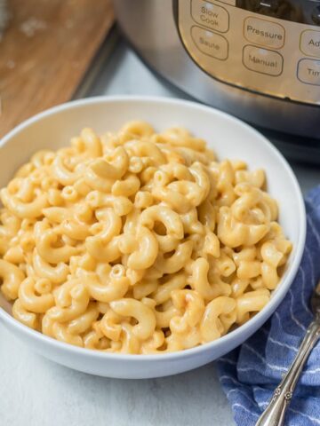 Bowl of Creamy Macaroni and Cheese next to Instant Pot