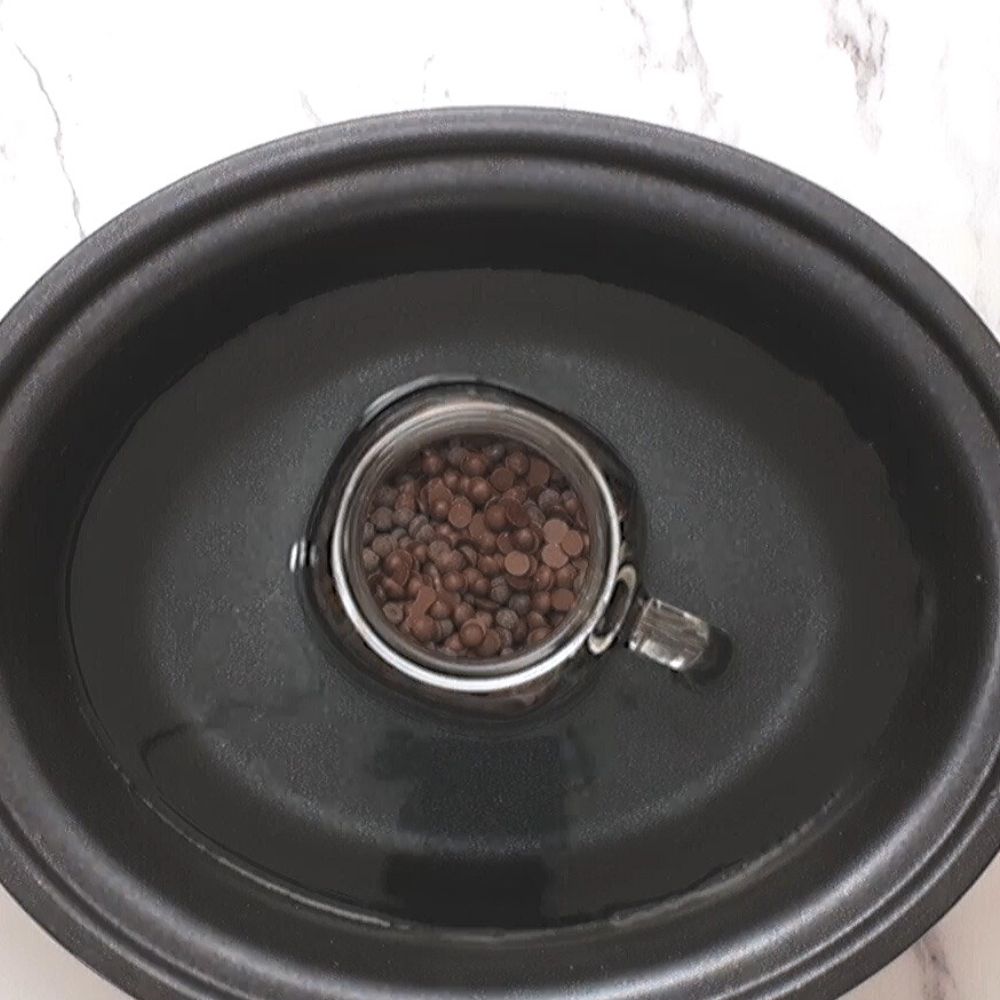 Glass jar of chocolate chips in slow cooker.