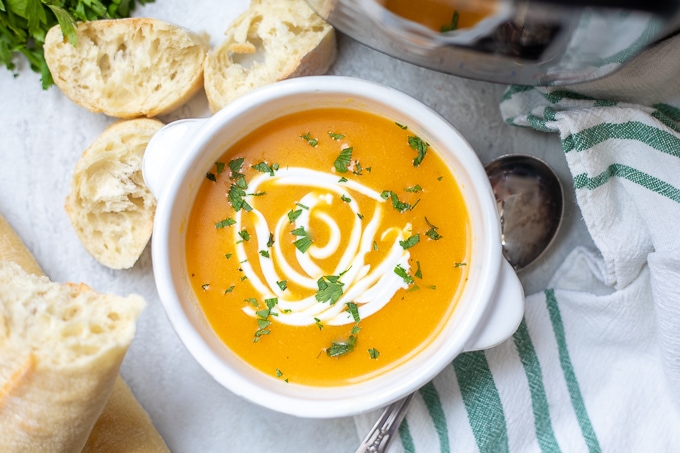 Instant Pot Butternut Squash and Apple Soup in white bowl next to sliced bread.