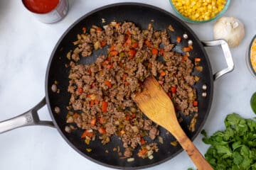 Ground beef sauteed with onion pepper in skillet.