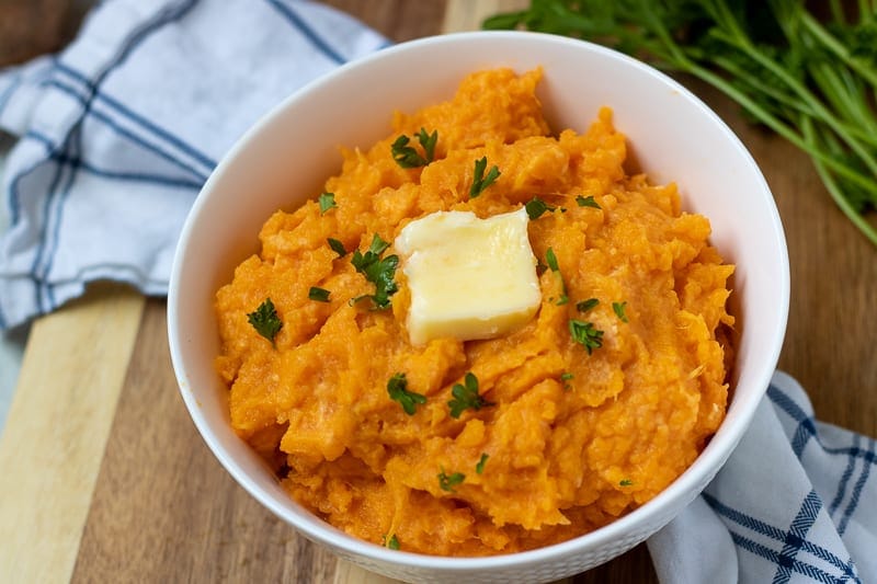 Healthy mashed Sweet Potatoes with Butter in white bowl. 