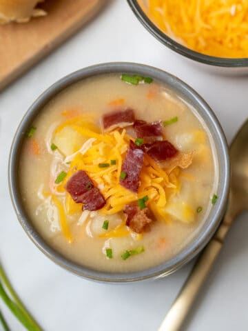 Bowl of potato soup topped with cheese and bacon.