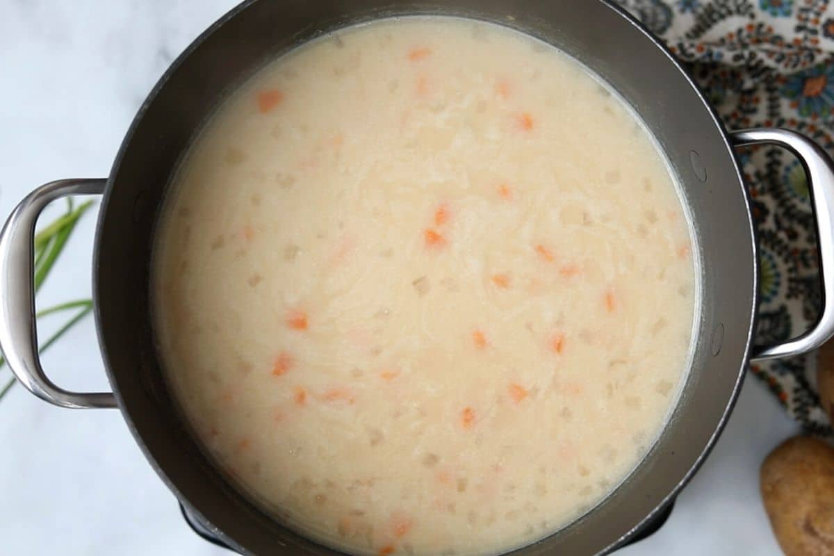 Creamy potato soup in saucepan on stove. 