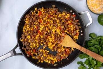 Skillet with corn, seasoning, ground beef for tamale pie.