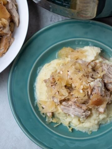Pork and Sauerkraut served on mashed potatoes on blue plate