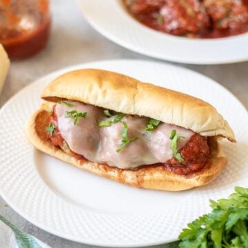 Meatball Sub on white plate next to meatballs