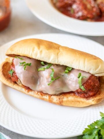 Meatball Sub on white plate next to meatballs