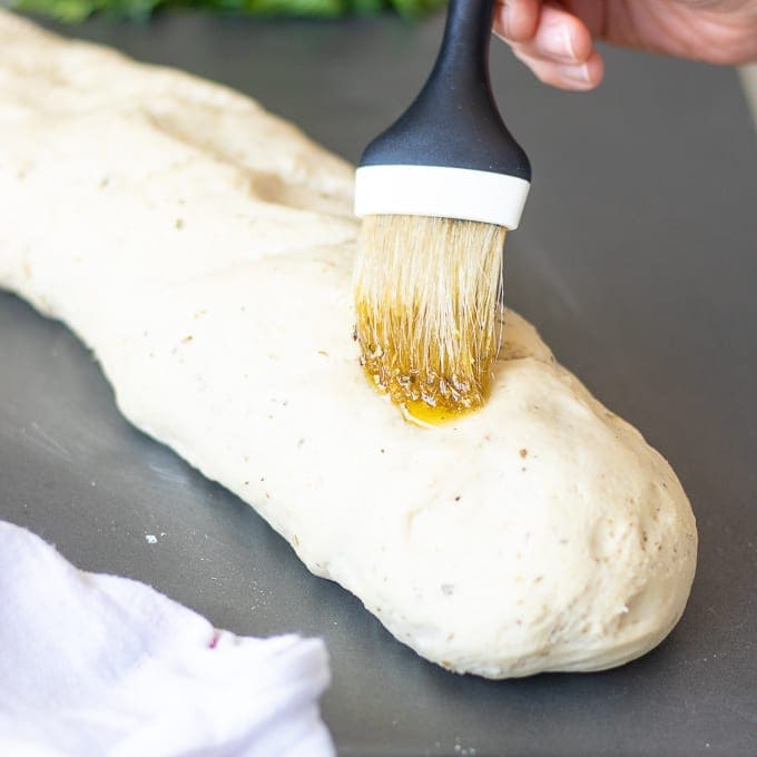 Olive oil being brushed on Italian Bread Dough