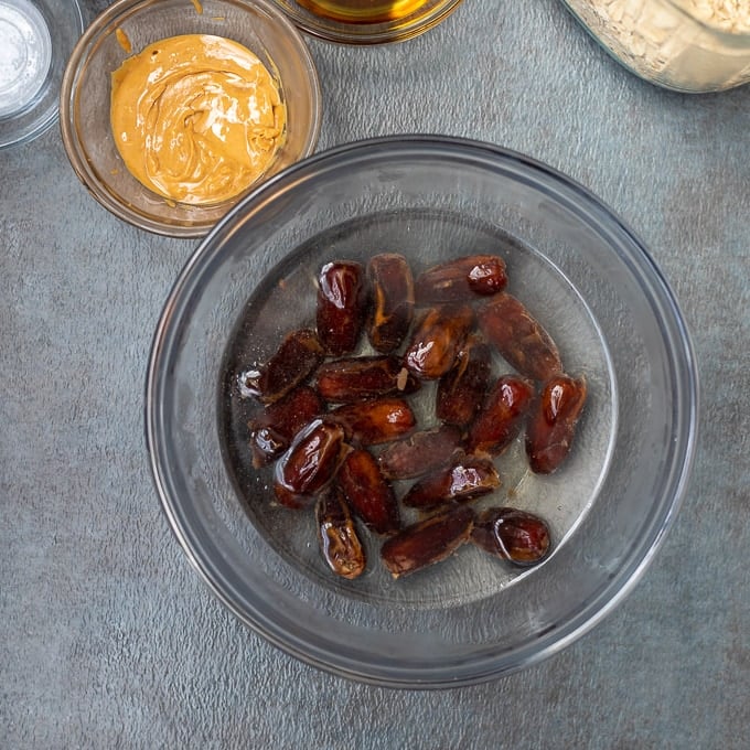 Dates soaking in hot water next to oats.