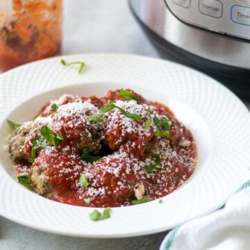 Bowl of Instant Pot Meatballs with tomato sauce next to pressure cooker