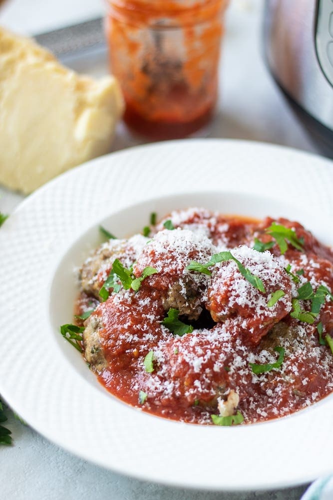 Bowl of Meatballs covered in tomato sauce next to instant Pot.