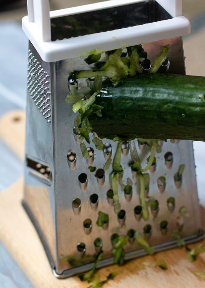 Grating an English Cucumber on a box grater.