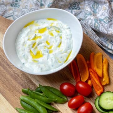 Bowl of Tzatziki Sauce topped with olive oil with fresh veggies
