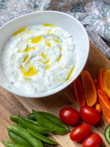 Bowl of Tzatziki Sauce topped with olive oil with fresh veggies
