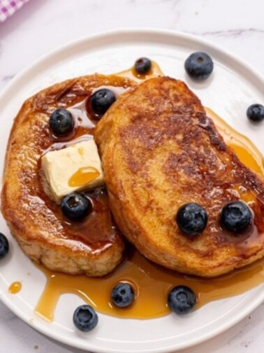 two slices of perfect french toast with maple syrup on white plate