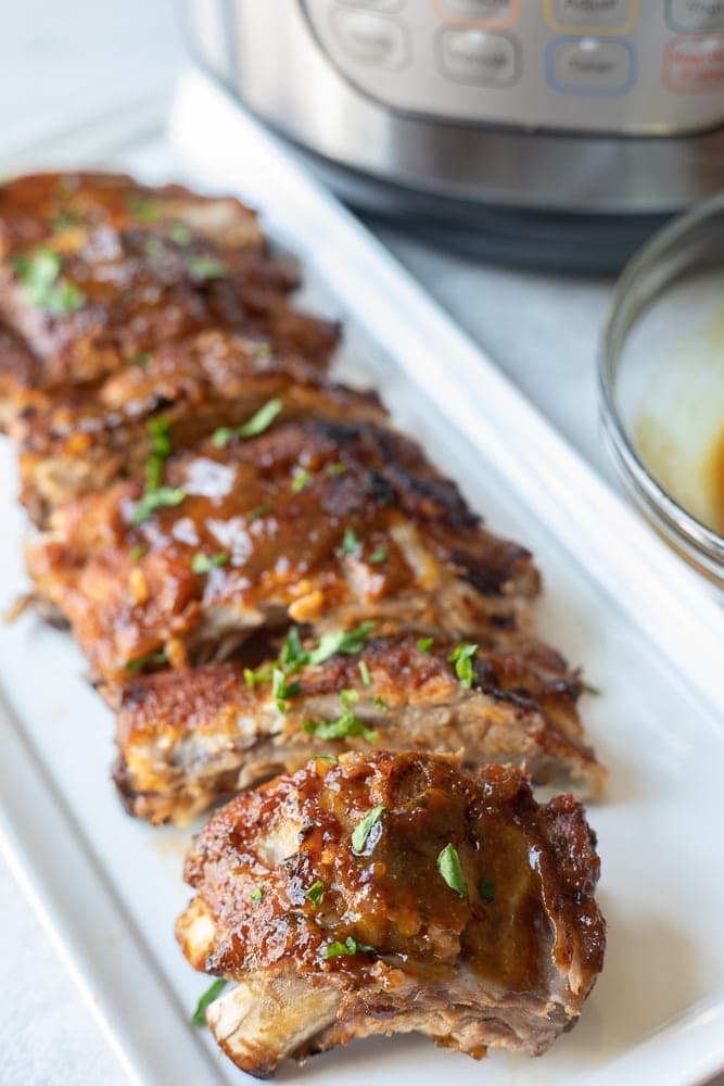 Barbecue Ribs on white platter next Instant Pot