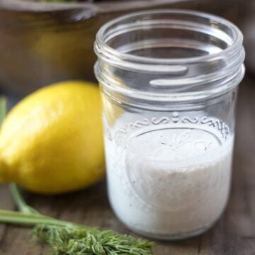 Jar of homemade ranch dressing next to dill