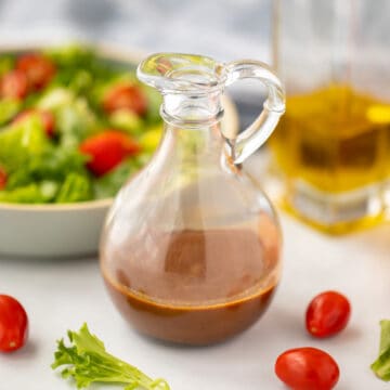 Balsamic Dressing in glass pitcher next to tossed salad.