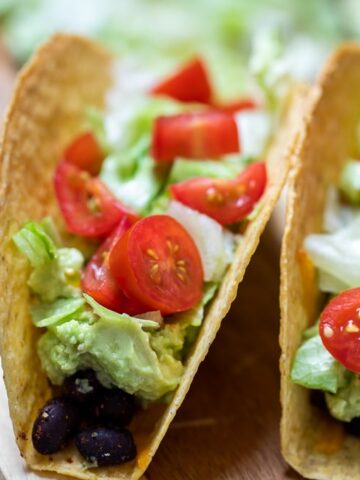 Close up of baked black bean tacos topped with lettuce and tomatoes.