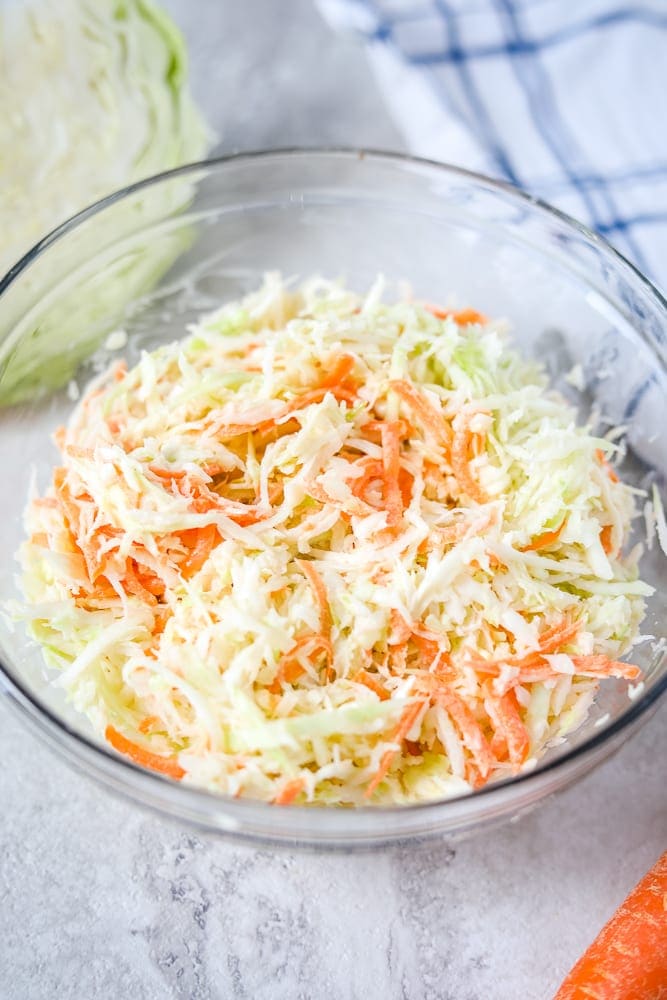 Bowl of Coleslaw next to green cabbage