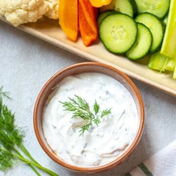 Bowl of homemade dill Dip next to platter of vegetables.