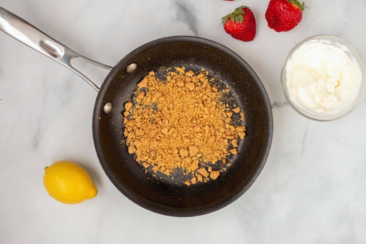 Toasted Graham crackers in skillet next to small bowl of sour cream. 