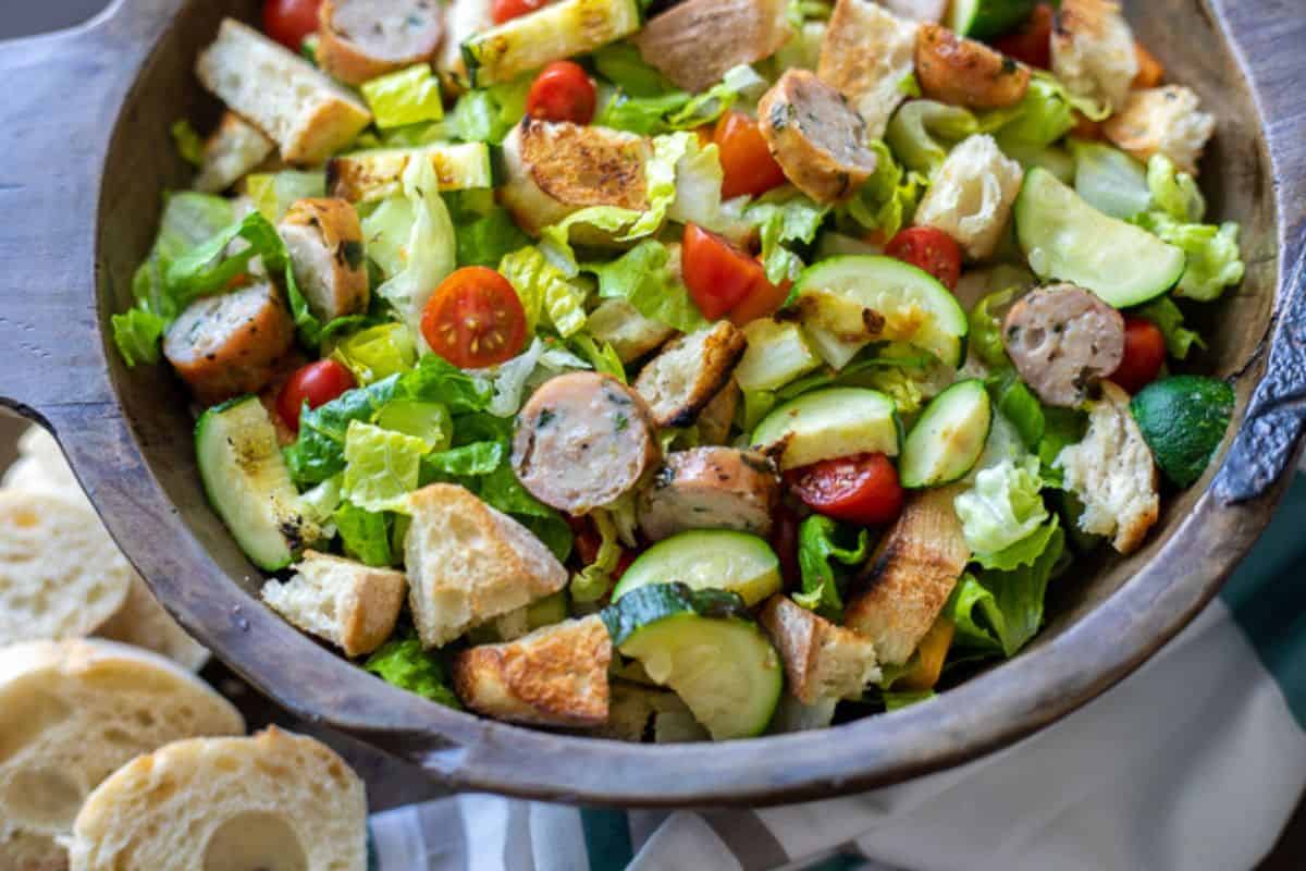 Grilled Panzanella Salad with chicken sausage in large wooden bowl. 