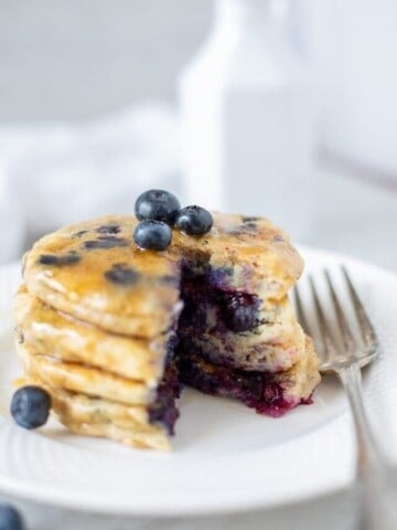 Blueberry Pancakes on white plate with bite cut out