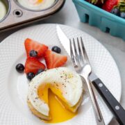 Poached egg cut open to reveal runny yolk on white plate